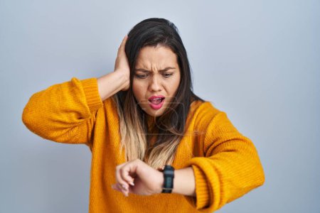 Photo for Young hispanic woman standing over isolated background looking at the watch time worried, afraid of getting late - Royalty Free Image