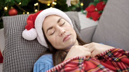 Foto de Mujer caucásica joven con sombrero de Navidad durmiendo en el sofá en casa - Imagen libre de derechos