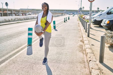 Photo for African american woman wearing sportswear stretching leg at street - Royalty Free Image