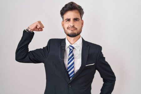 Photo for Young hispanic man with tattoos wearing business suit and tie strong person showing arm muscle, confident and proud of power - Royalty Free Image