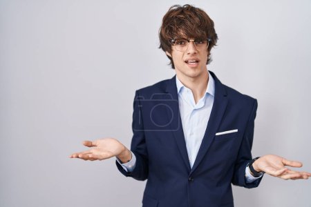 Photo for Hispanic business young man wearing glasses clueless and confused with open arms, no idea concept. - Royalty Free Image