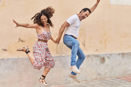 Téléchargez les photos : Homme et femme couple souriant confiant dansant dans la rue - en image libre de droit