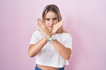 Téléchargez les photos : Jeune femme blonde debout sur fond rose expression de rejet croisant les bras faisant signe négatif, visage en colère - en image libre de droit