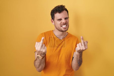 Téléchargez les photos : Young hispanic man standing over yellow background showing middle finger doing fuck you bad expression, provocation and rude attitude. screaming excited - en image libre de droit