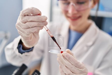 Téléchargez les photos : Jeune femme blonde scientifique versant du sang sur l'échantillon au laboratoire - en image libre de droit