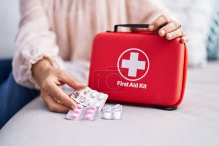 Photo for Middle age grey-haired woman holding pills and first aid kit at street - Royalty Free Image