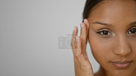 Téléchargez les photos : Jeune femme latine touchant les yeux baggy avec les doigts sur fond blanc isolé - en image libre de droit