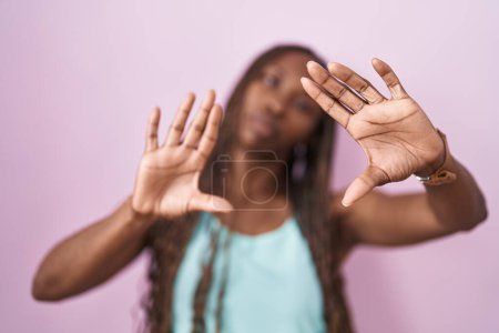 Photo for African american woman standing over pink background doing frame using hands palms and fingers, camera perspective - Royalty Free Image