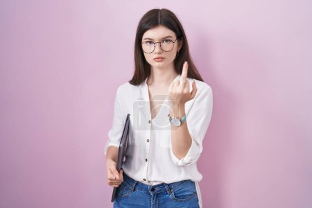 Téléchargez les photos : Young caucasian woman holding laptop showing middle finger, impolite and rude fuck off expression - en image libre de droit