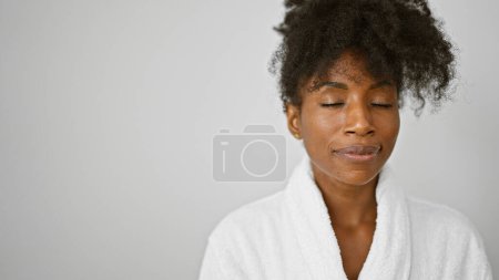 Foto de Mujer afroamericana con albornoz de pie con cara seria sobre fondo blanco aislado - Imagen libre de derechos