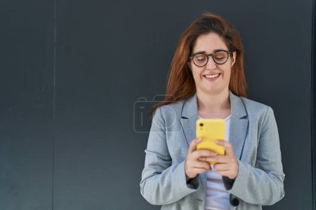 Photo for Young woman business worker smiling confident using smartphone over black isolated background - Royalty Free Image