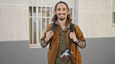 Foto de Joven turista hispano con mochila sonriendo en la calle - Imagen libre de derechos