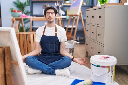 Photo for Young hispanic man artist relaxed doing yoga exercise at art studio - Royalty Free Image