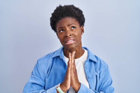 Photo for African american woman standing over blue background begging and praying with hands together with hope expression on face very emotional and worried. begging. - Royalty Free Image