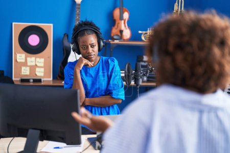Téléchargez les photos : Musiciennes afro-américaines parlant avec une expression sérieuse au studio de musique - en image libre de droit