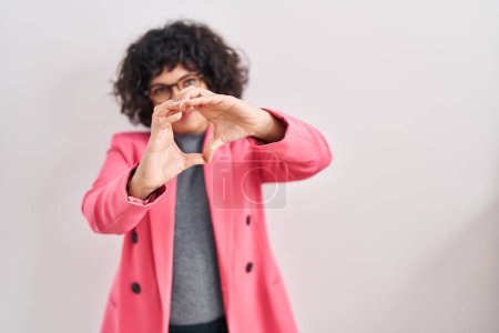 Photo for Hispanic woman with curly hair standing over isolated background smiling in love doing heart symbol shape with hands. romantic concept. - Royalty Free Image