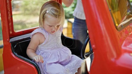 Téléchargez les photos : Caucasien bébé fille jouer heureux assis sur swing à la aire de jeux parc - en image libre de droit
