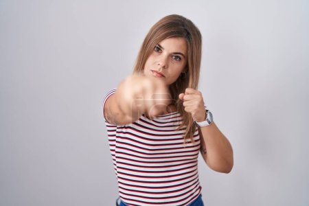 Téléchargez les photos : Jeune femme hispanique debout sur un arrière-plan isolé poing de poing pour se battre, attaque agressive et en colère, menace et violence - en image libre de droit