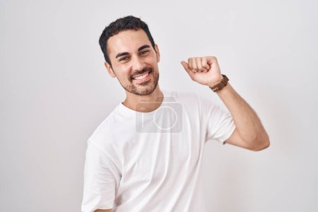Téléchargez les photos : Bel homme hispanique debout sur fond blanc dansant heureux et joyeux, souriant décontracté et confiant écoutant de la musique - en image libre de droit