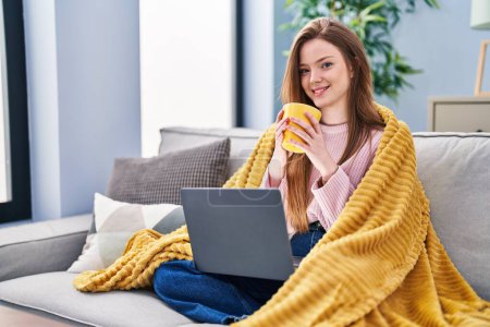 Photo for Young caucasian woman using laptop drinking coffee at home - Royalty Free Image