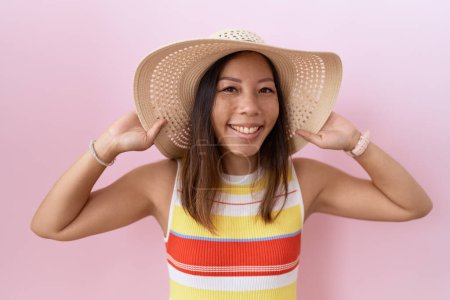 Photo for Middle age chinese woman wearing summer hat over pink background smiling and laughing hard out loud because funny crazy joke. - Royalty Free Image