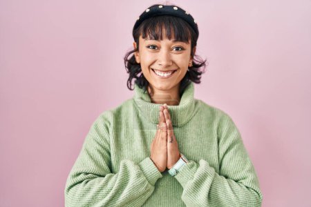 Téléchargez les photos : Young beautiful woman standing over pink background praying with hands together asking for forgiveness smiling confident. - en image libre de droit
