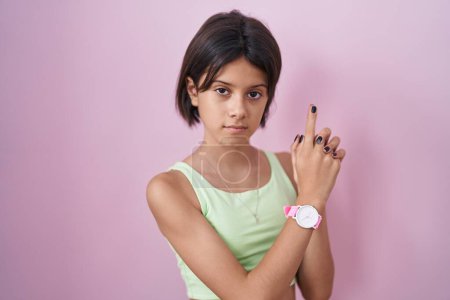 Photo for Young girl standing over pink background holding symbolic gun with hand gesture, playing killing shooting weapons, angry face - Royalty Free Image