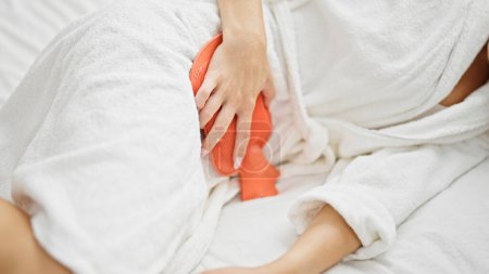 Foto de Mujer rubia joven que sufre de dolor menstrual acostada en la cama en el dormitorio - Imagen libre de derechos
