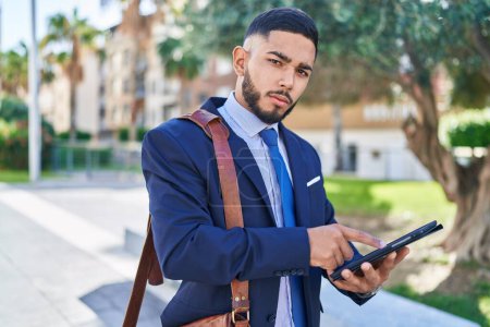 Photo for Young latin man business worker using touchpad with serious expression at park - Royalty Free Image