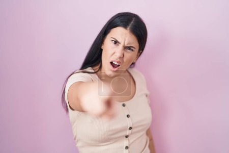 Foto de Young hispanic woman standing over pink background pointing displeased and frustrated to the camera, angry and furious with you - Imagen libre de derechos