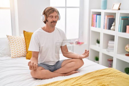 Téléchargez les photos : Young blond man doing yoga exercise sitting on bed at bedroom - en image libre de droit