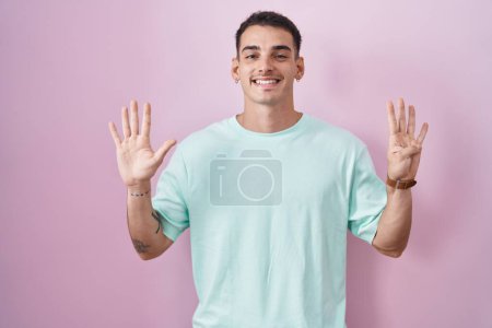 Téléchargez les photos : Bel homme hispanique debout sur fond rose montrant et pointant vers le haut avec les doigts numéro neuf tout en souriant confiant et heureux. - en image libre de droit