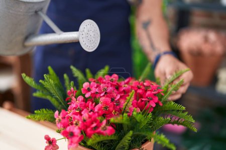 Foto de Joven florista hispano regando planta en floristería - Imagen libre de derechos