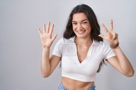 Photo for Young teenager girl standing over white background showing and pointing up with fingers number eight while smiling confident and happy. - Royalty Free Image