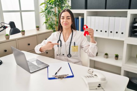 Photo for Hispanic doctor woman holding support red ribbon pointing finger to one self smiling happy and proud - Royalty Free Image