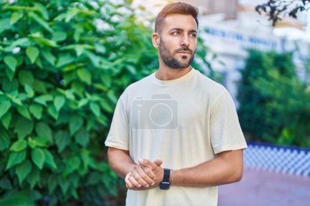 Téléchargez les photos : Jeune homme hispanique regardant vers le côté avec une expression sérieuse au parc - en image libre de droit