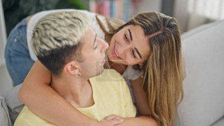 Téléchargez les photos : Beau couple s'embrassant assis sur le canapé à la maison - en image libre de droit