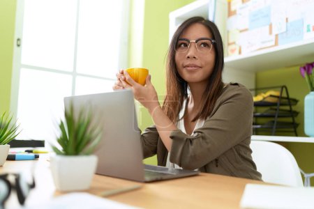 Foto de Joven asiático mujer de negocios trabajador usando portátil beber café en oficina - Imagen libre de derechos