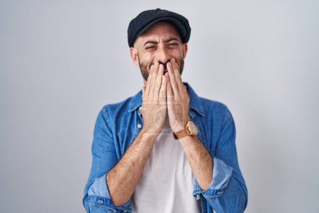 Téléchargez les photos : Homme hispanique avec barbe debout sur fond isolé rire et rire embarrassé couvrant la bouche avec les mains, commérages et concept scandaleux - en image libre de droit