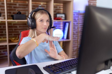 Téléchargez les photos : Jeune femme caucasienne jouant à des jeux vidéo portant un casque faisant un geste avec les mains, frustré et sérieux visage - en image libre de droit