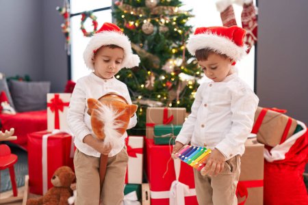 Foto de Adorables chicos jugando juguete de caballo celebración xilófono Navidad en casa - Imagen libre de derechos
