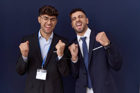 Photo for Two hispanic business men wearing business clothes excited for success with arms raised and eyes closed celebrating victory smiling. winner concept. - Royalty Free Image