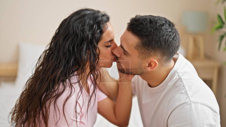 Téléchargez les photos : Man and woman couple sitting on bed kissing at bedroom - en image libre de droit