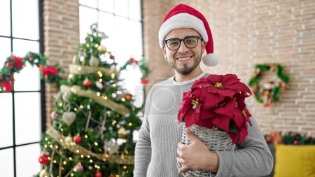 Foto de Hombre hispano sosteniendo planta de Navidad en casa - Imagen libre de derechos