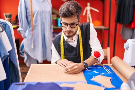 Téléchargez les photos : Jeune homme hispanique tailleur faire marque sur le tissu à l'atelier - en image libre de droit