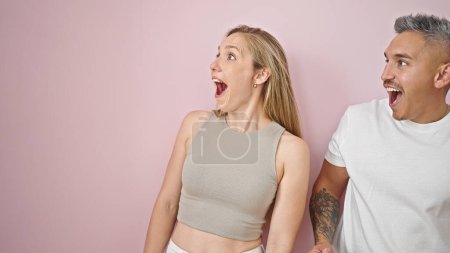 Téléchargez les photos : Couple homme et femme regardant sur le côté surpris sur fond rose isolé - en image libre de droit