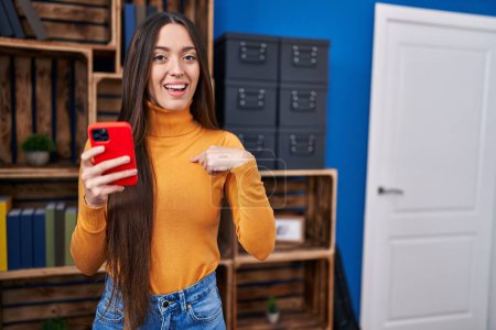 Photo for Young brunette woman using smartphone pointing finger to one self smiling happy and proud - Royalty Free Image