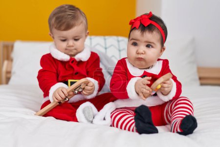 Téléchargez les photos : Adorable garçon et fille portant des vêtements de Noël tenant hochet dans la chambre - en image libre de droit