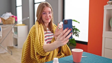 Téléchargez les photos : Jeune femme blonde utilisant un smartphone ayant une consultation médicale en ligne à la salle à manger - en image libre de droit