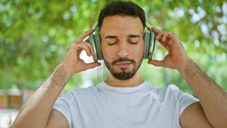Téléchargez les photos : Jeune homme arabe écoutant de la musique au parc - en image libre de droit
